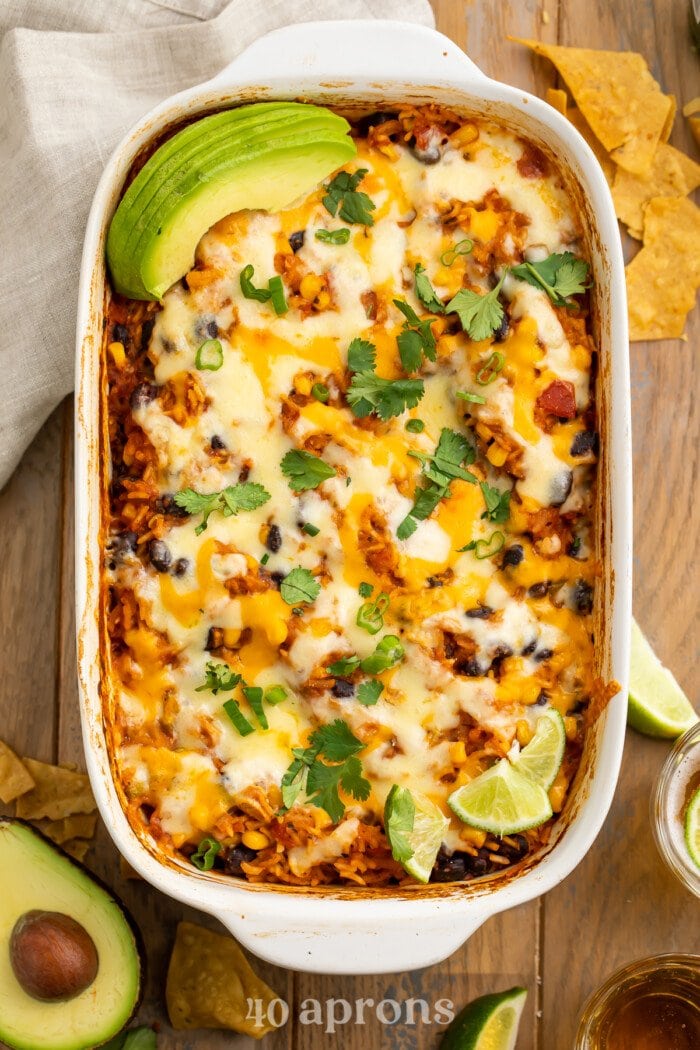 Overhead view of a large white casserole dish holding a Mexican rice casserole with rice, beans, and cheese.