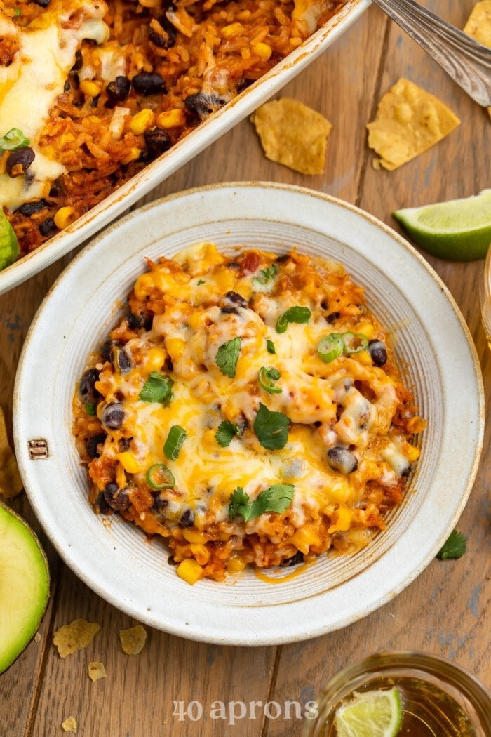 Overhead view of a serving of Mexican rice casserole in a bowl next to a large casserole dish.