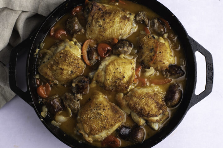 Overhead view of chicken scarpariello in a large cast iron skillet.