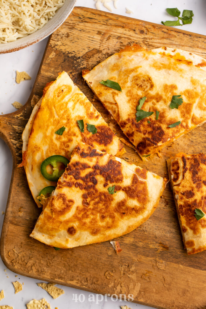 Chicken tikka masala quesadilla quarters on a wooden cutting board.