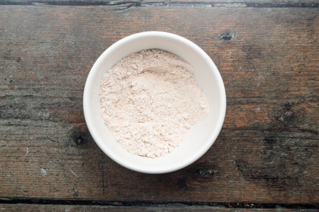 Overhead view of all-purpose flour and Old Bay seasoning mixed together in a white mixing bowl.