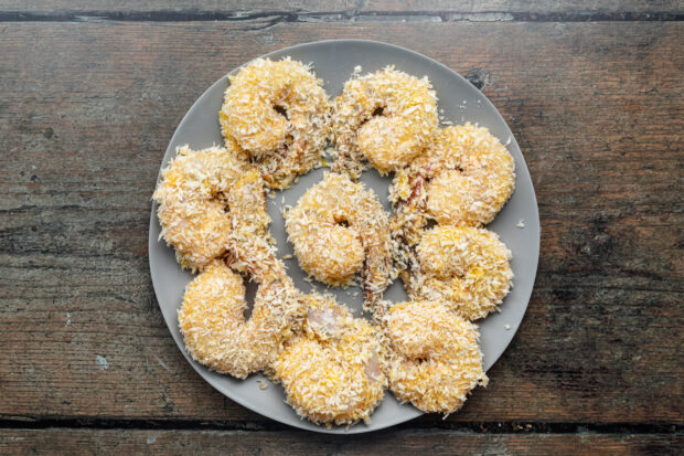 Overhead view of bread, uncooked shrimp in a circle on a plate.