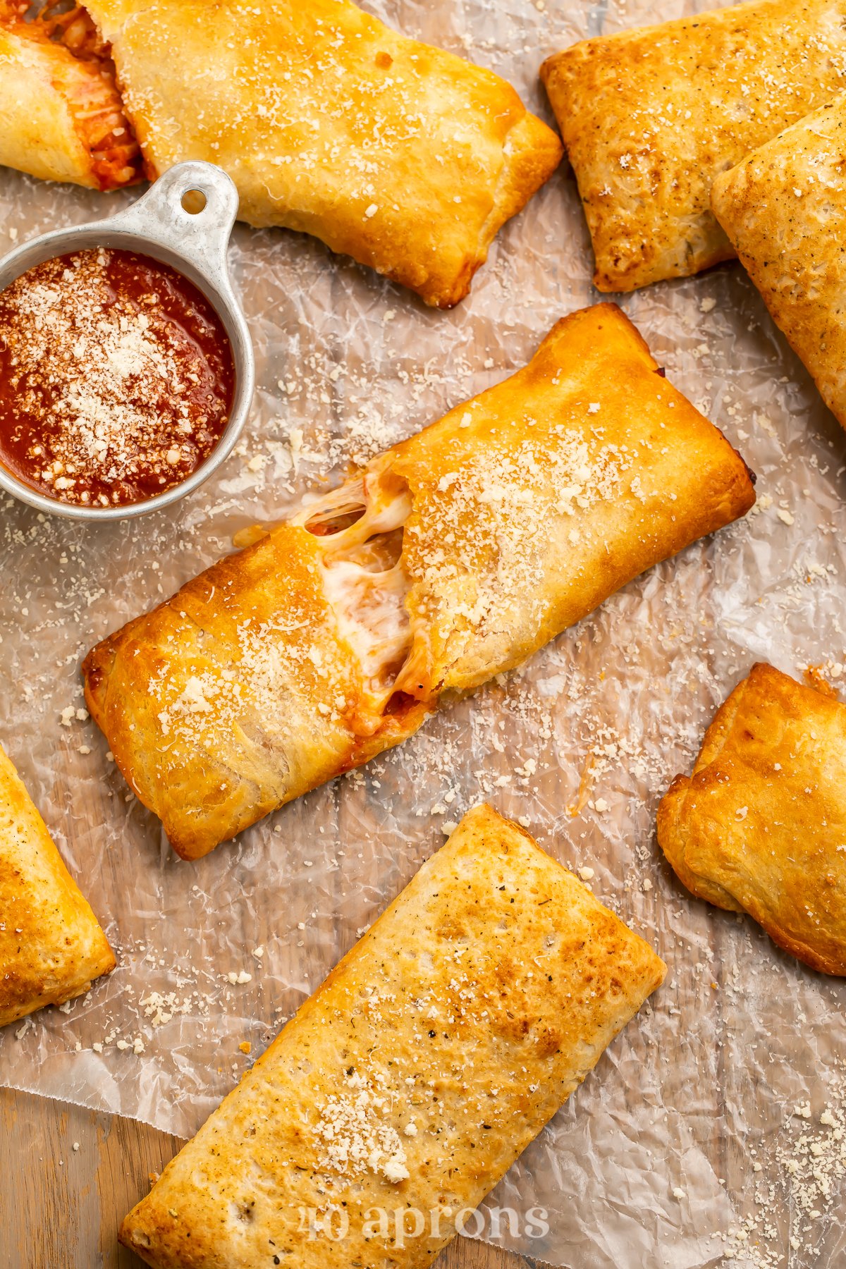 Overhead view of air fryer hot pockets (frozen and homemade) on parchment paper with pizza sauce.