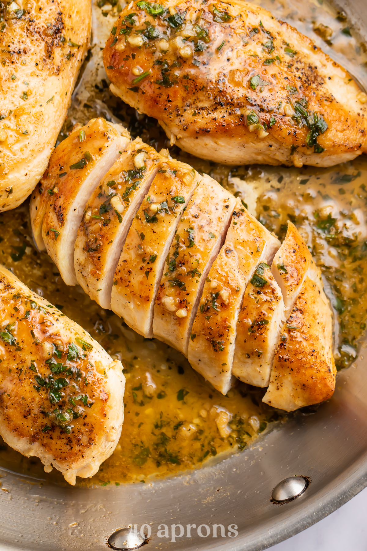 Overhead view of a garlic butter chicken breast sliced diagonally into strips on a skillet.