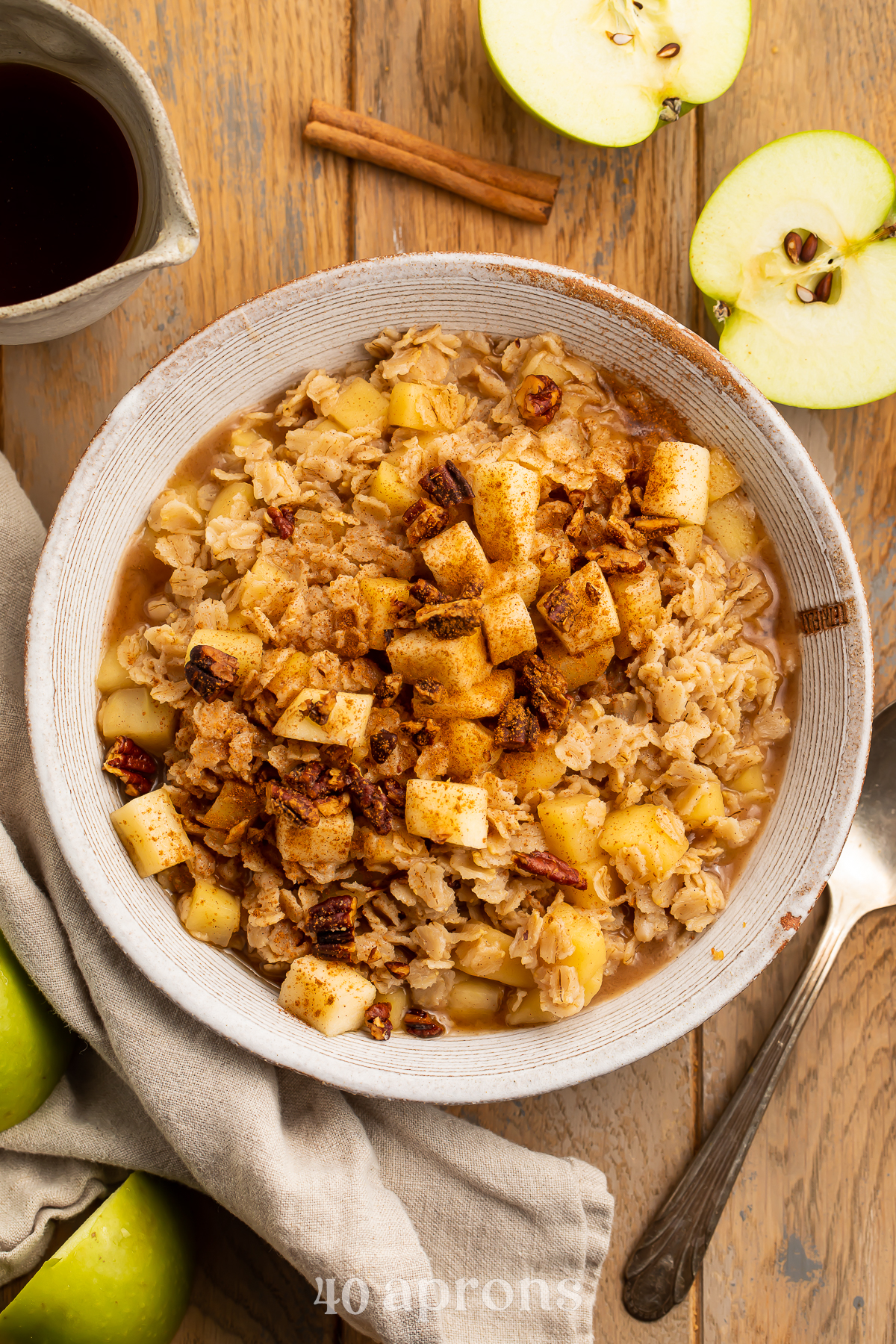 Overhead view of a large bowl of apple cinnamon oatmeal topped with brown sugar and cinnamon on a wooden table.