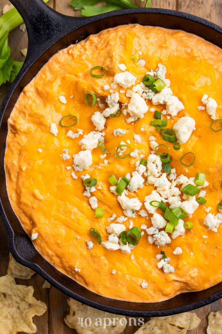 Overhead view of Instant Pot buffalo chicken dip in a cast-iron skillet. Dip is topped with blue cheese crumbles and green onions.