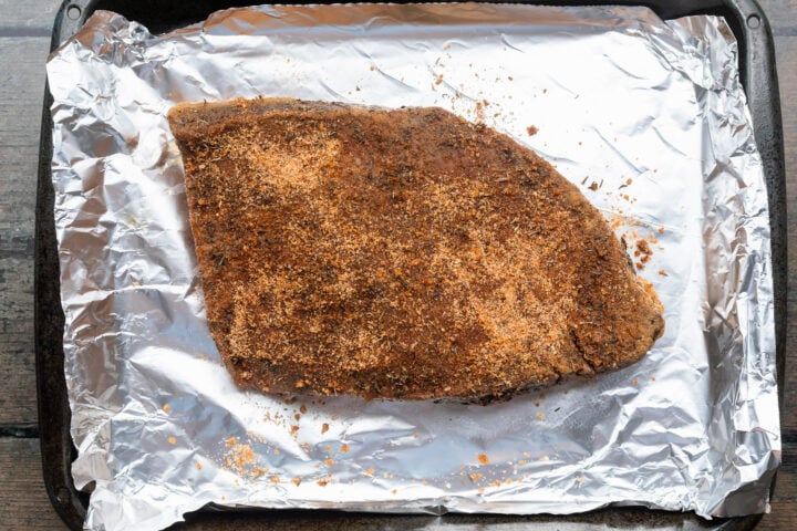 Seasoned sous vide brisket on a sheet pan lined with aluminum foil.