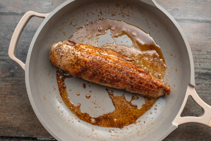 Overhead view of sous vide pork tenderloin in a large skillet, seared until golden brown on top.