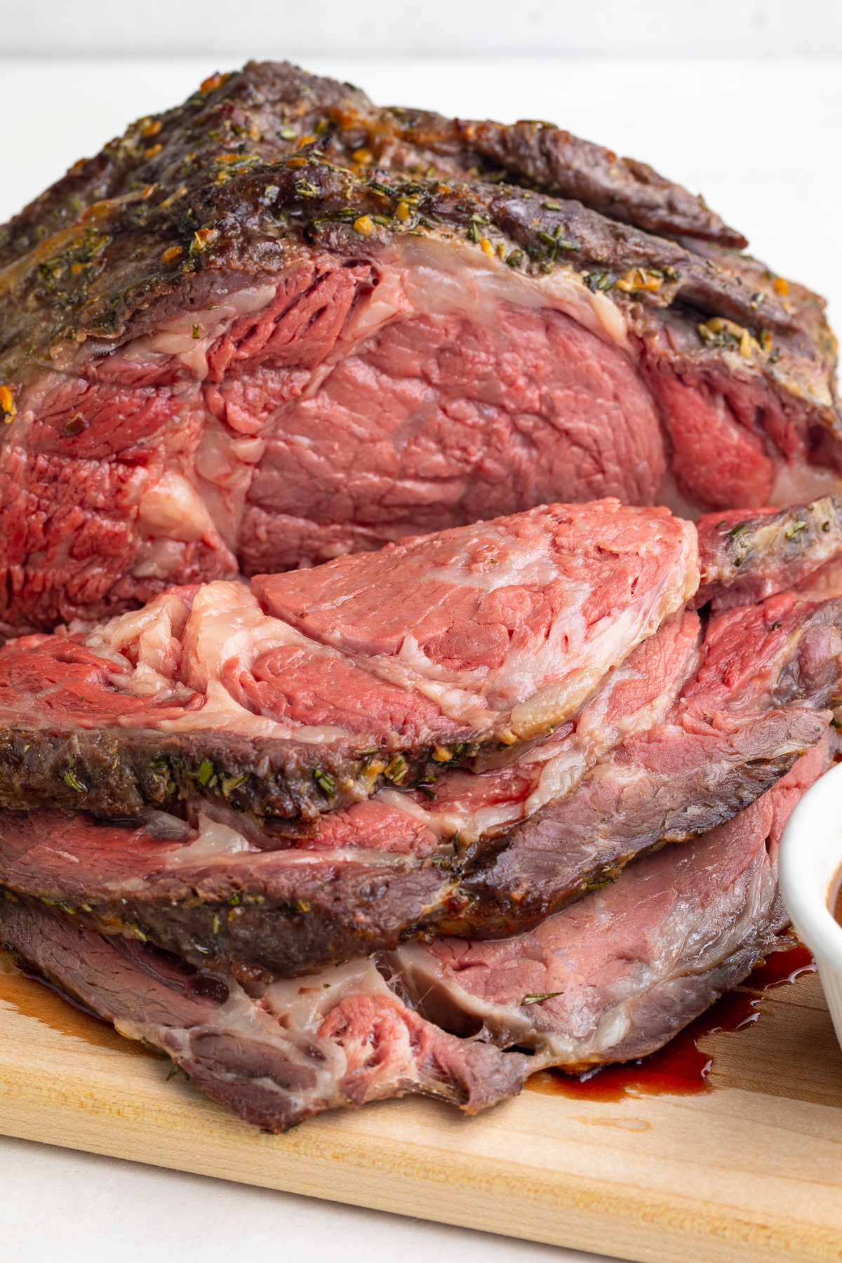 Close-up look at a carved sous vide prime rib on a wooden cutting board in front of a white background.