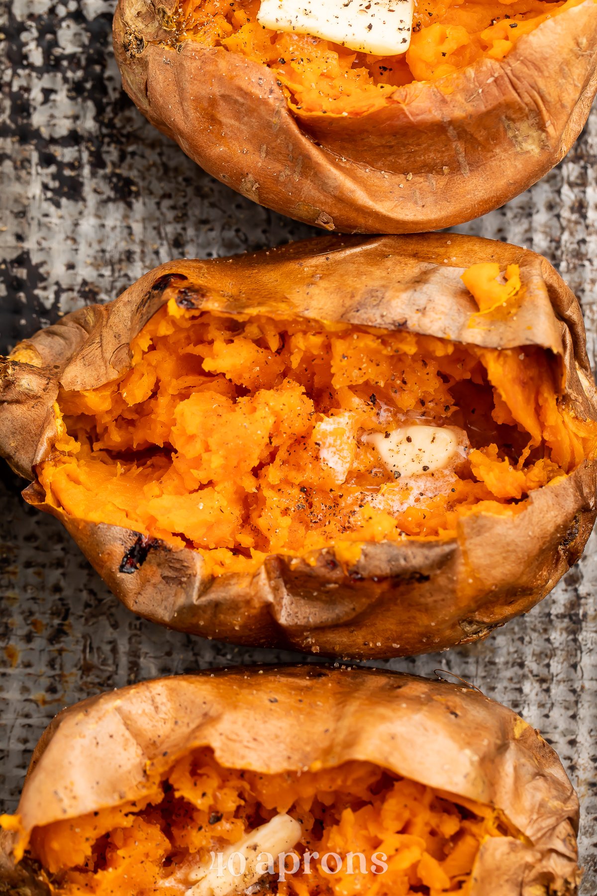 Overhead view of a vertical row of cut-open sweet potatoes on a sheet of foil.