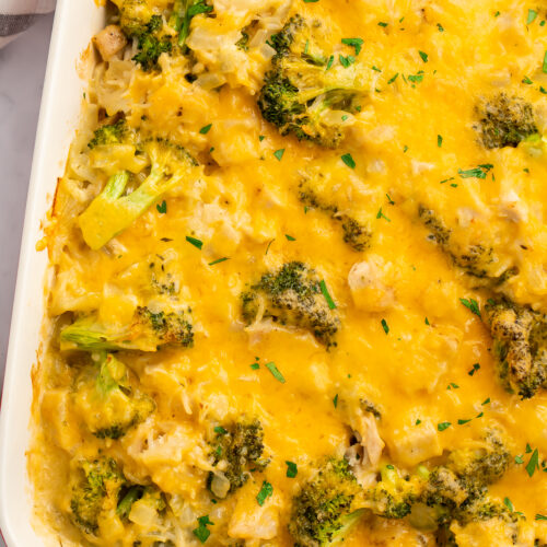 Overhead view of a white rectangular casserole dish angled from the top right corner of the image. Dish contains a baked chicken broccoli rice casserole.