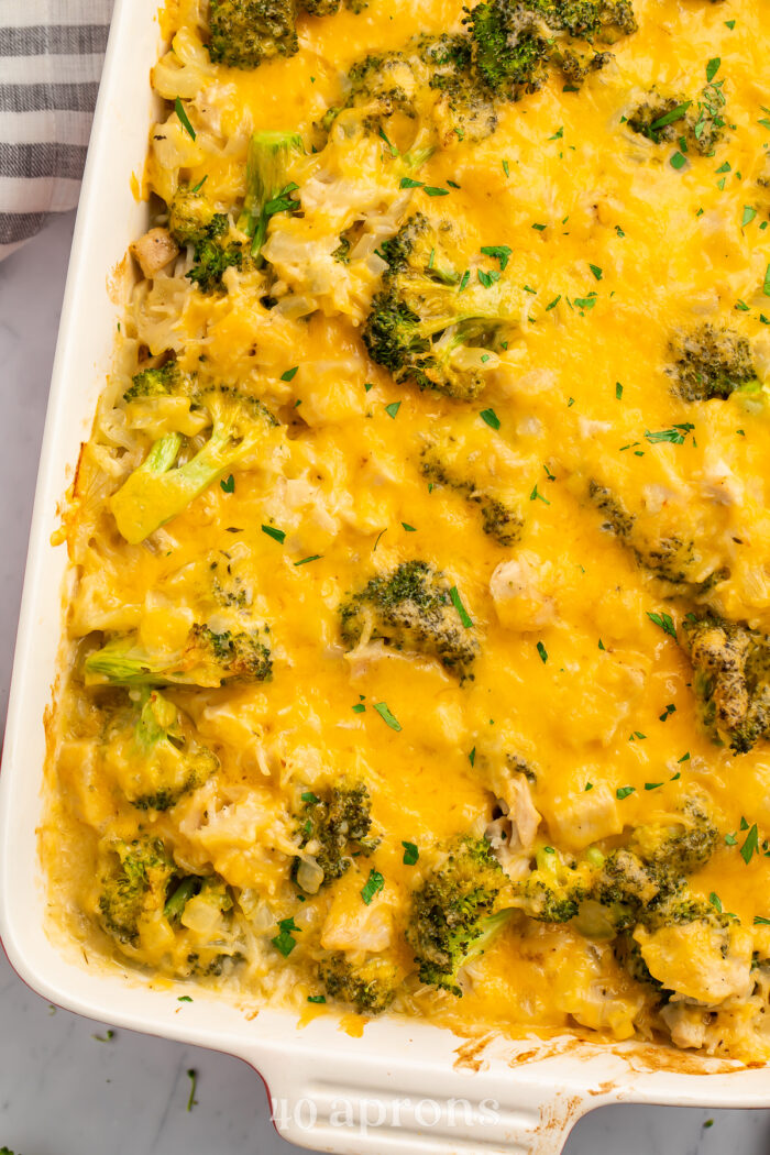 Overhead view of a white rectangular casserole dish angled from the top right corner of the image. Dish contains a baked chicken broccoli rice casserole.