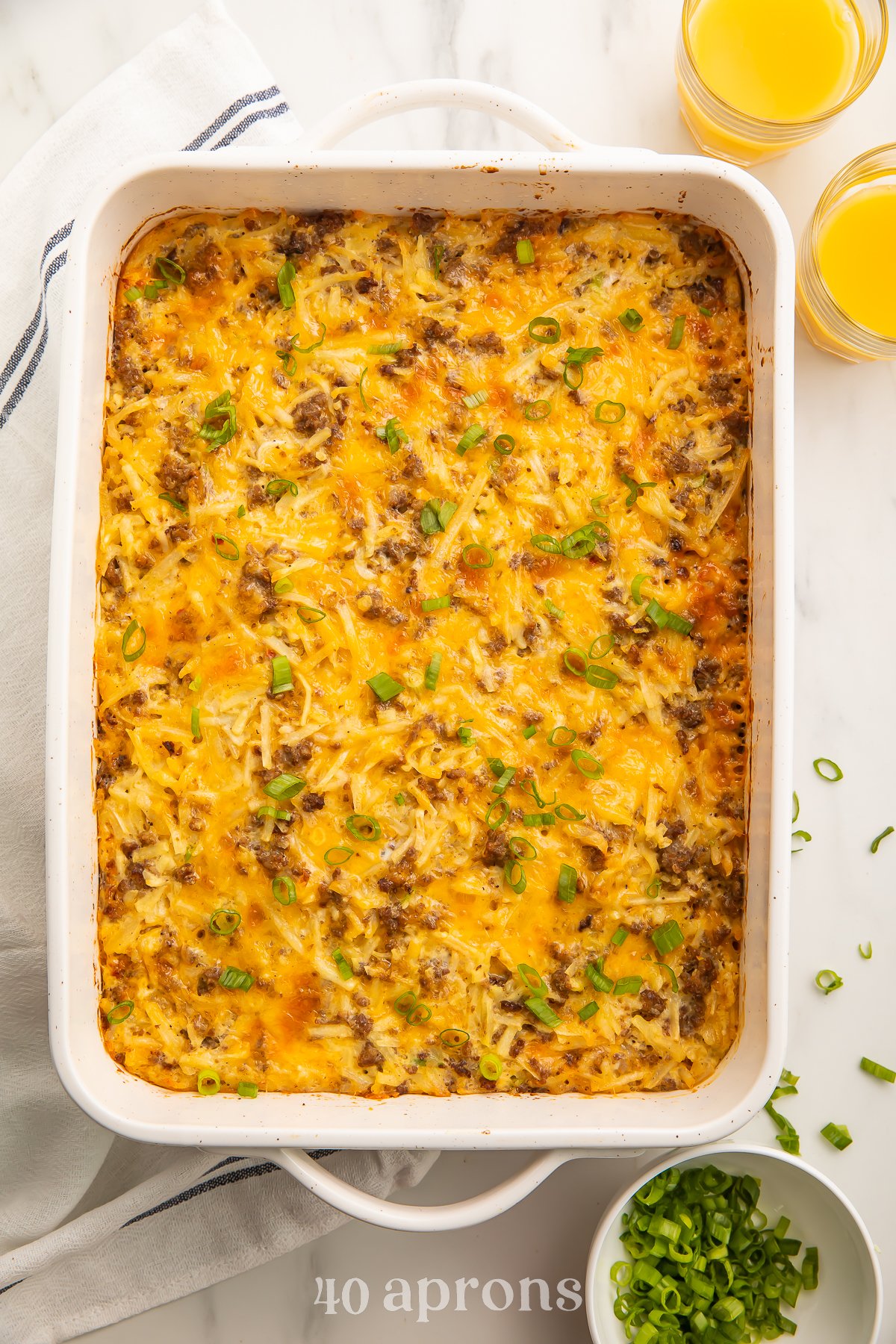 Overhead view of a rectangular casserole dish containing a fully baked gluten free breakfast casserole on a white table.