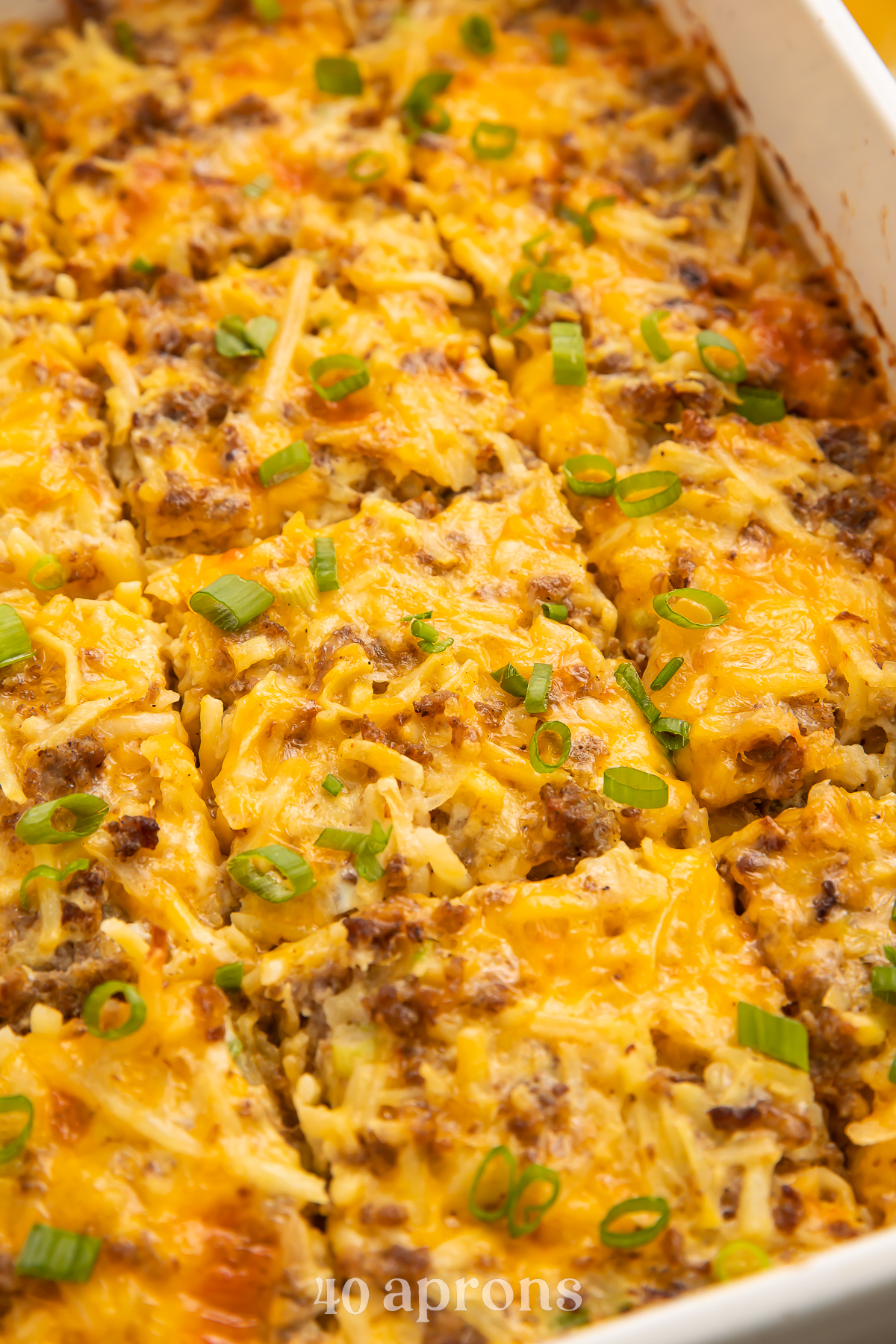 Angled photo of a rectangular white casserole dish with a fully-baked gluten free breakfast casserole cut into 12 squares.