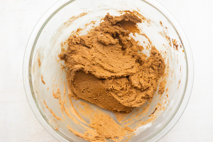 Gluten-free gingerbread cookie dough in a large glass mixing bowl.