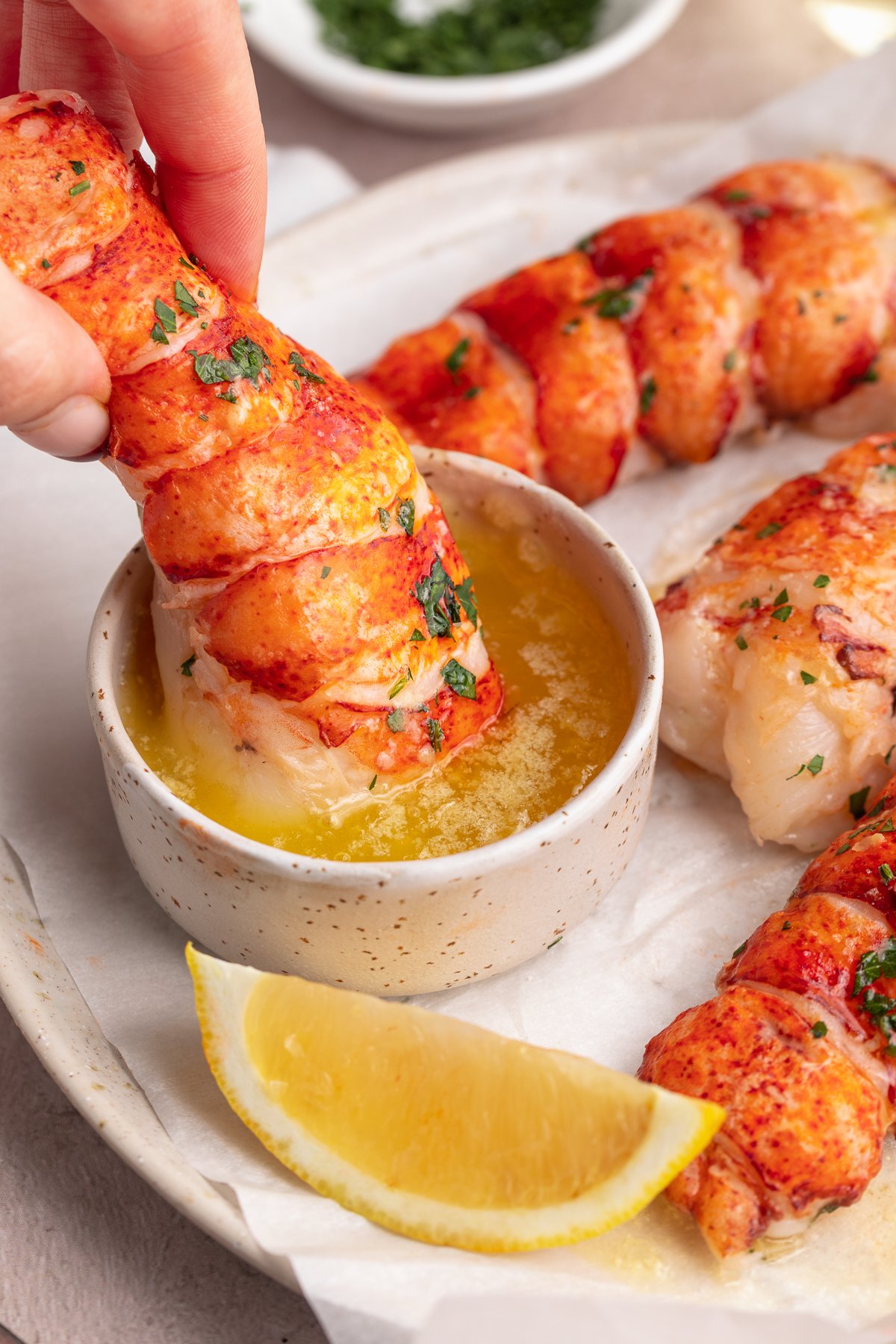 Sous vide cooked lobster meat being dipped into a ramekin of butter sauce.