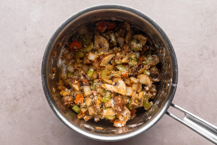 Overhead view of cubed sirloin steak with mushrooms and carrots in a large saucepan.z