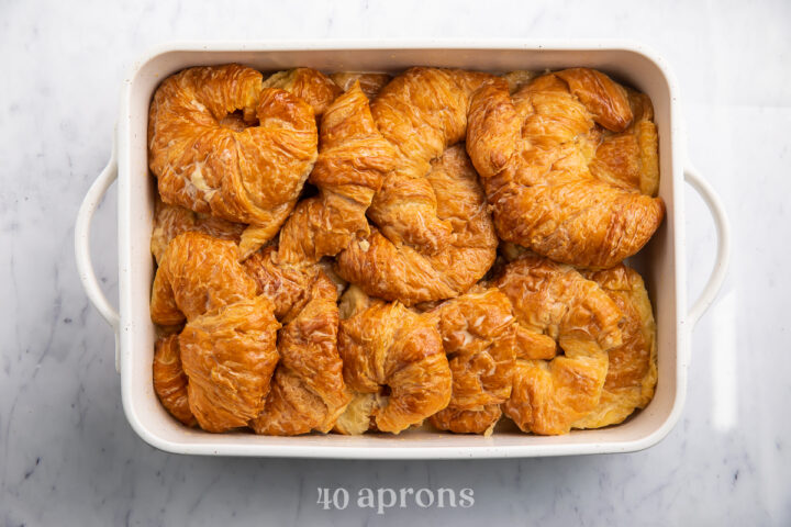 Overhead view of an unbaked croissant french toast casserole in a large rectangular casserole dish.