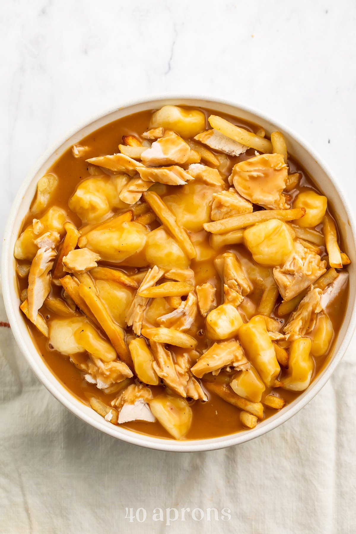 Overhead view of a bowl of leftover turkey poutine with fries. and gravy.