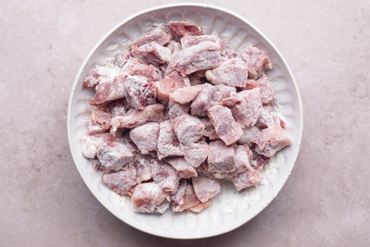 Chopped pork shoulder coated in flour resting on a plate.