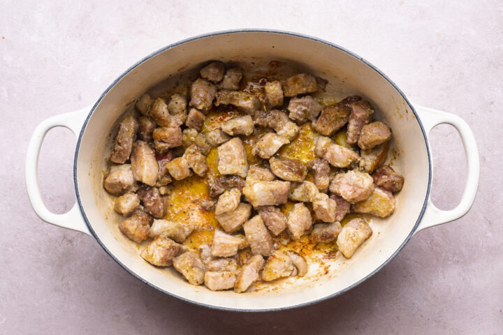 Overhead view of pork shoulder in a large oval dutch oven.