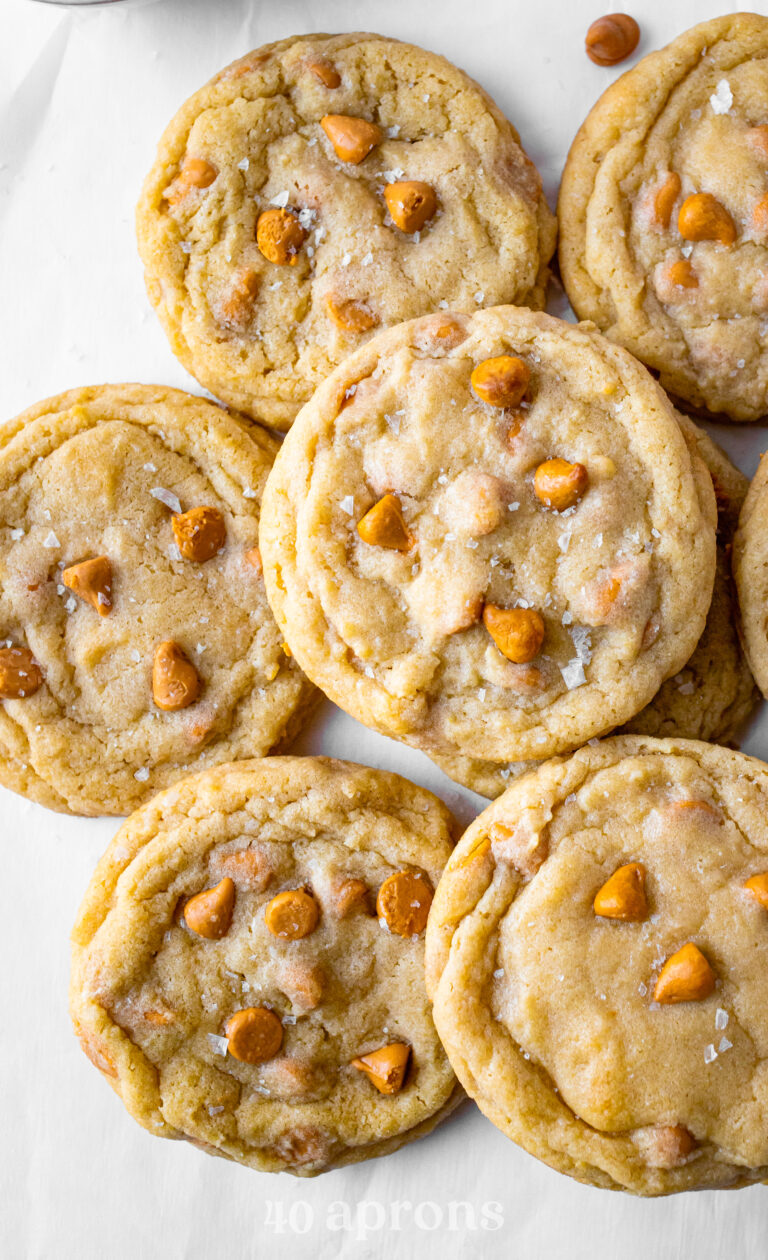 Overhead view of a pile of chewy butterscotch cookies on a neutral background.