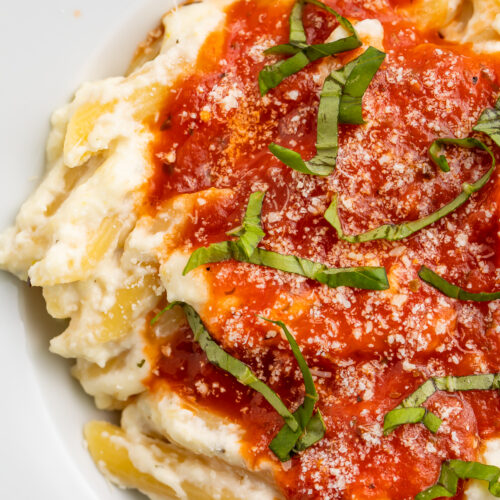 Close-up view of lemon ricotta pasta with marinara and parmesan.