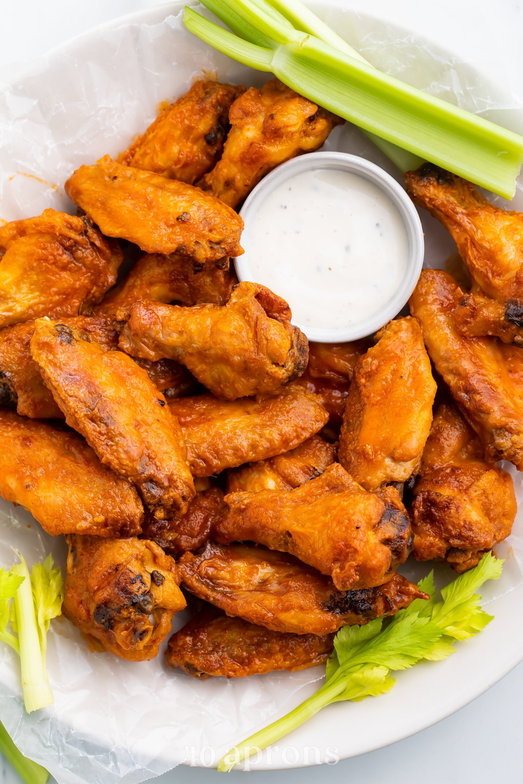 A large plate filled with Whole30 buffalo wings, celery stalks, and a small ramekin of Whole30 ranch dressing.