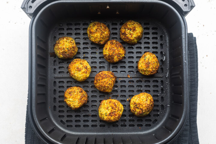 Crisp, golden brown air fryer falafel in an air fryer basket.