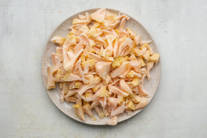 Hand-pulled shredded jackfruit on a white plate.