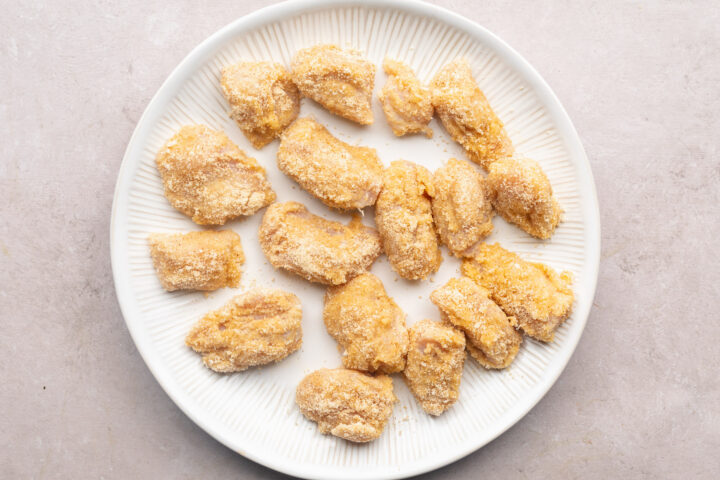 Keto chicken nuggets, breaded but not yet fried, on a white plate.