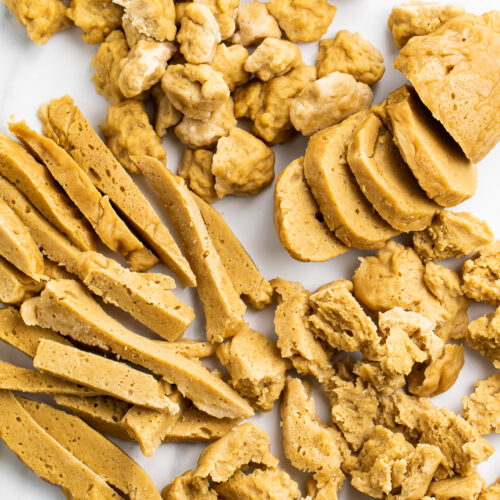 Overhead view of 4 different types of seitan on a marble countertop.