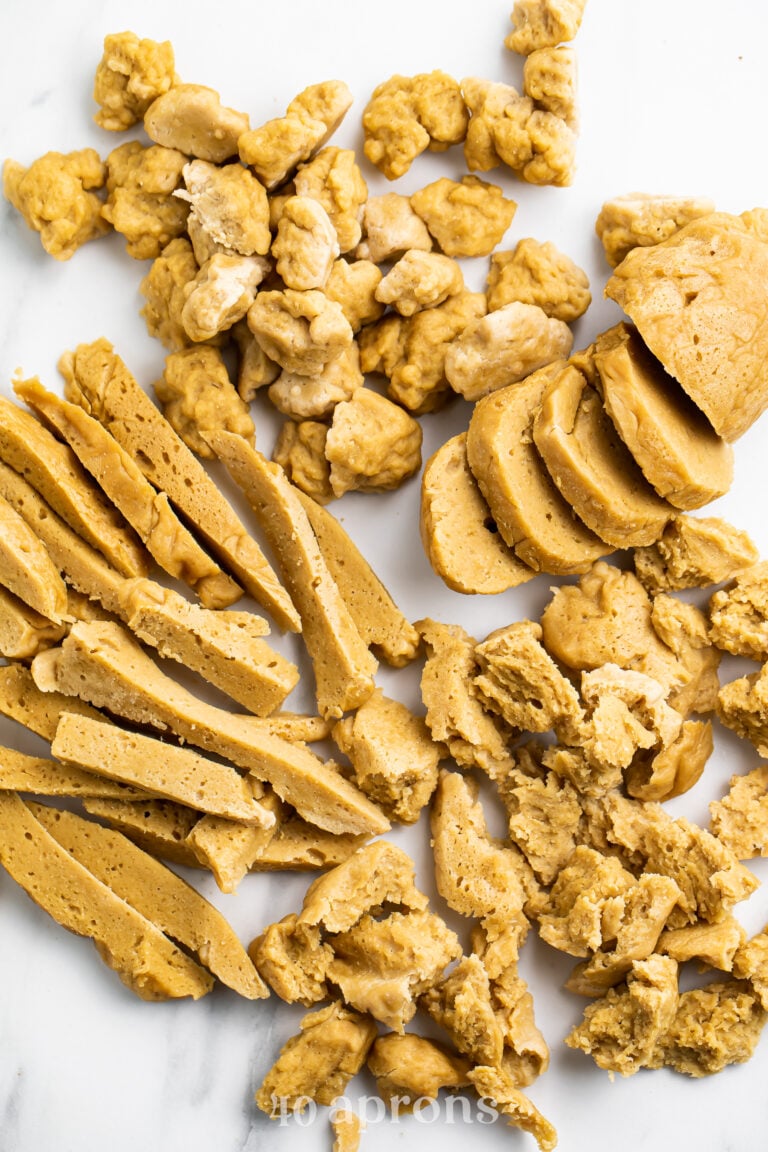 Overhead view of 4 different types of seitan on a marble countertop.