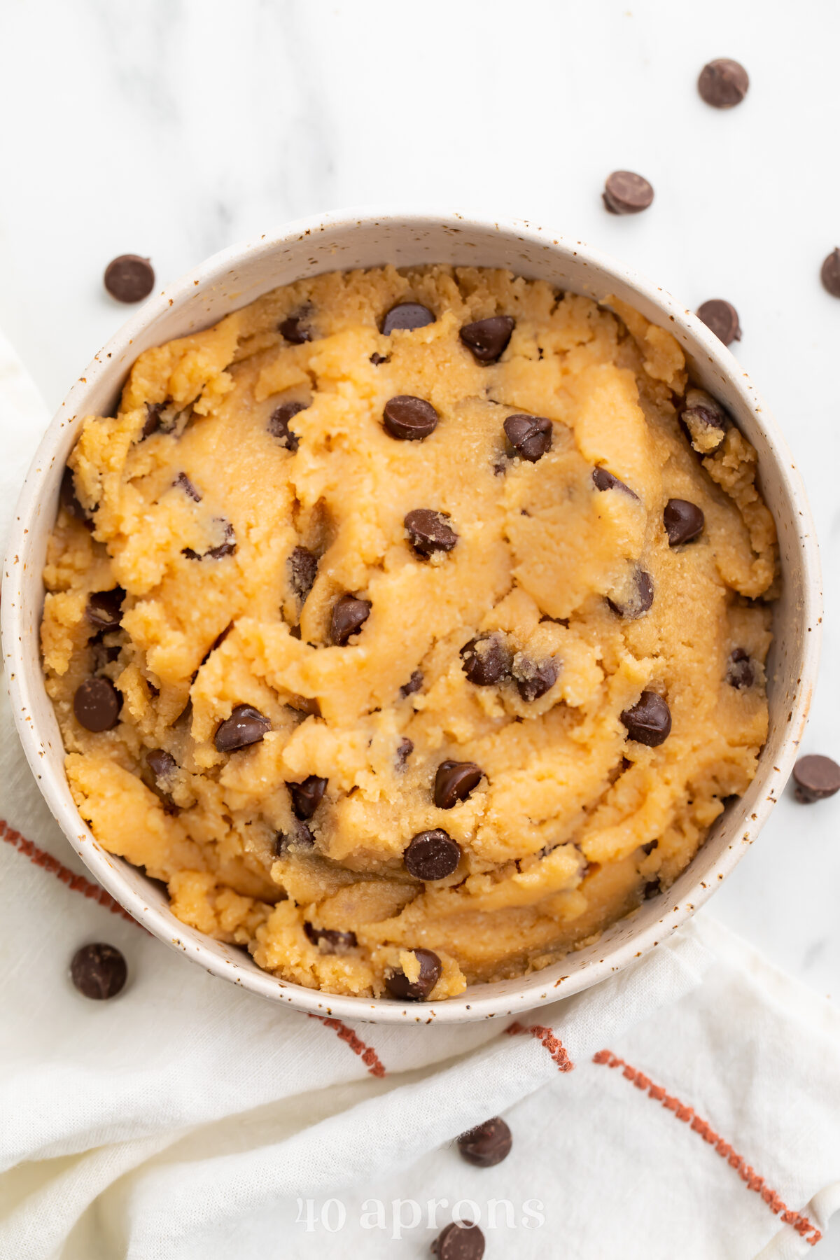 Keto cookie dough in a large bowl with keto chocolate chips sprinkled around the bowl.