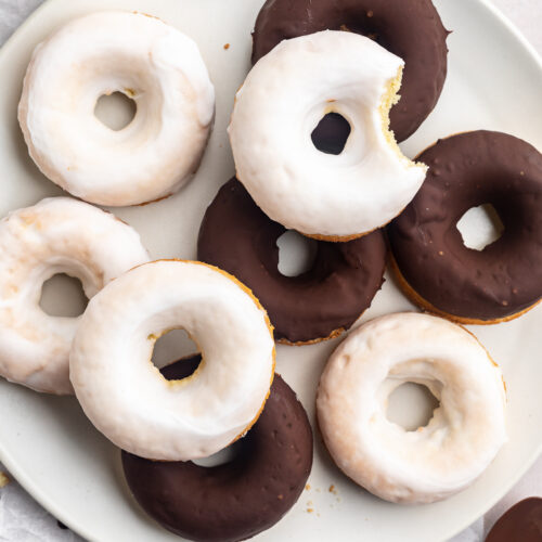 Overhead look at chocolate and vanilla glazed donuts piled up on a plate.