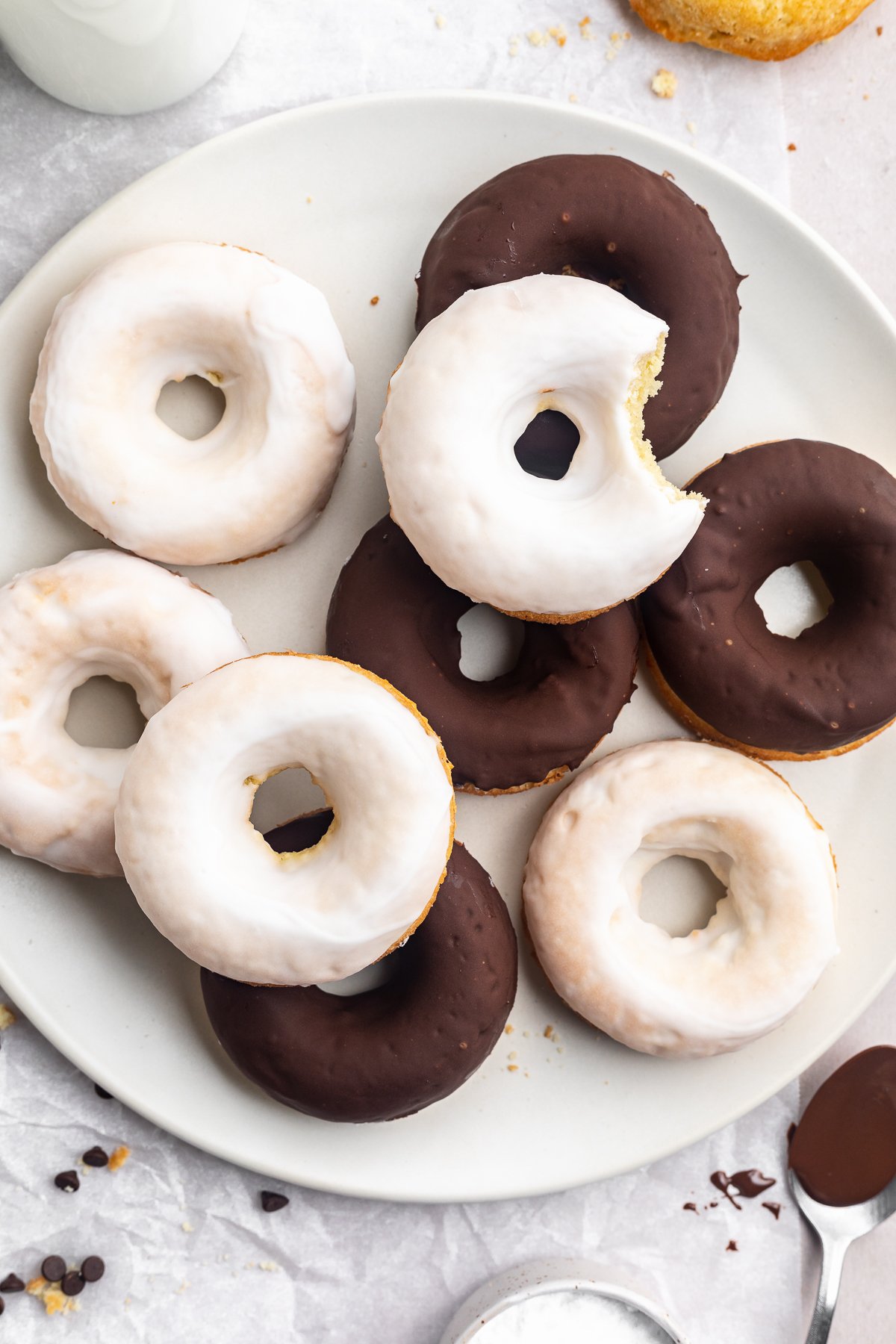 Overhead look at chocolate and vanilla glazed donuts piled up on a plate.