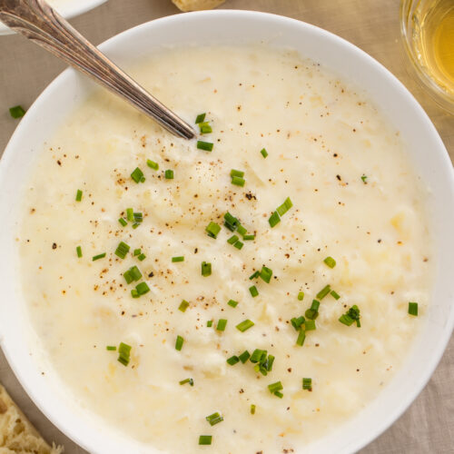 Top-down view of a bowl of creamy old-fashioned potato soup topped with green onions.