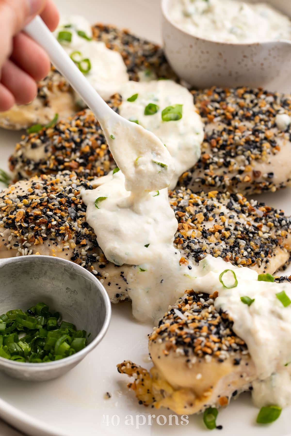 Dairy-free cream cheese sauce being spooned over Whole30 everything bagel chicken.