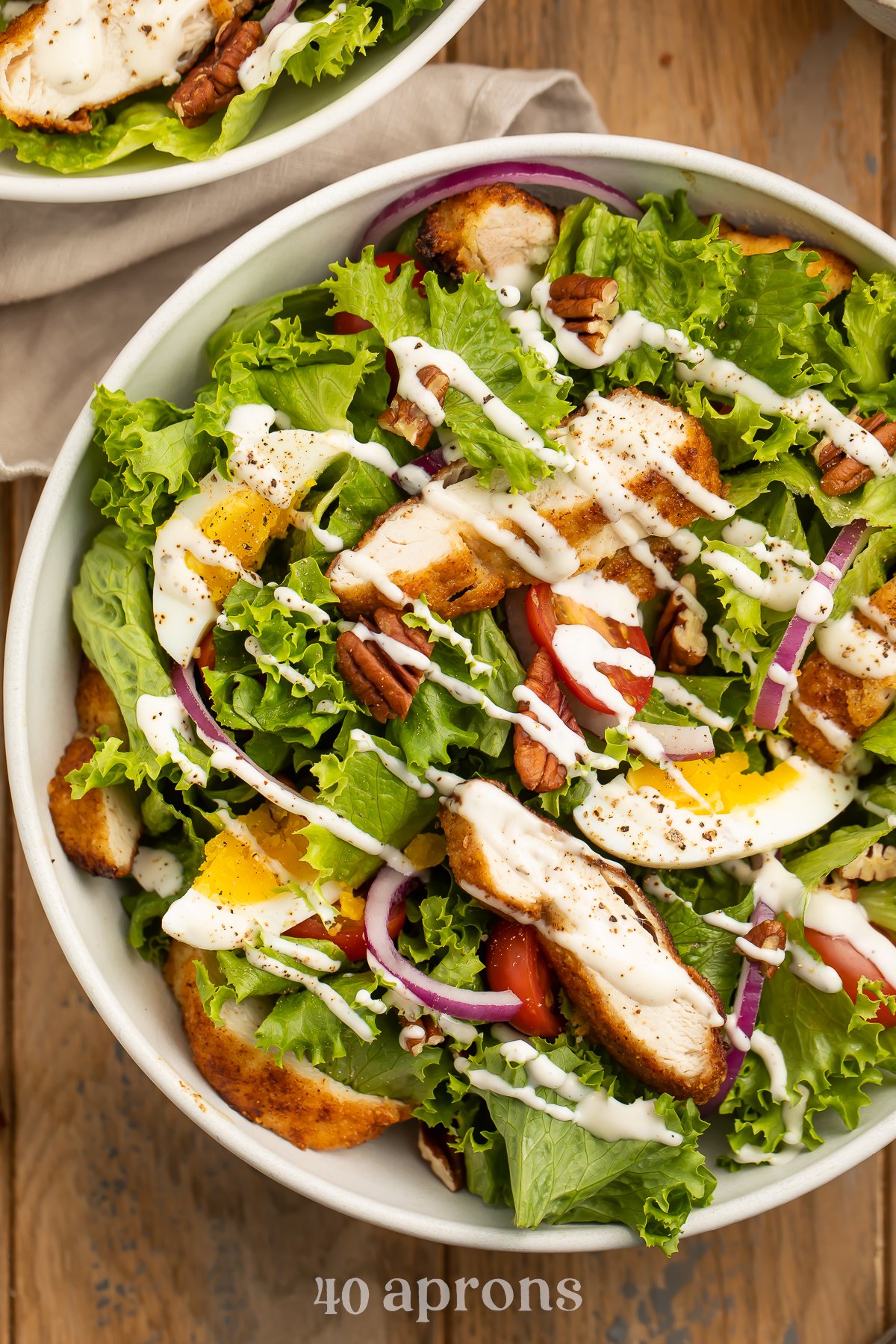 Whole30 southern fried chicken salad with lettuce, fried chicken, red onion, eggs, pecans, and ranch dressing.