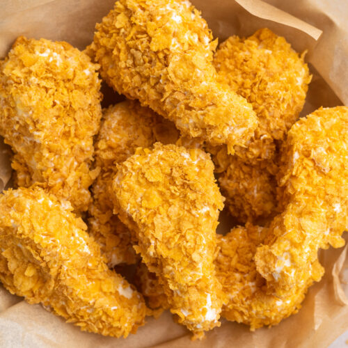 Overhead, top-down view of fried chicken ice cream drumsticks in a bowl lined with parchment paper.