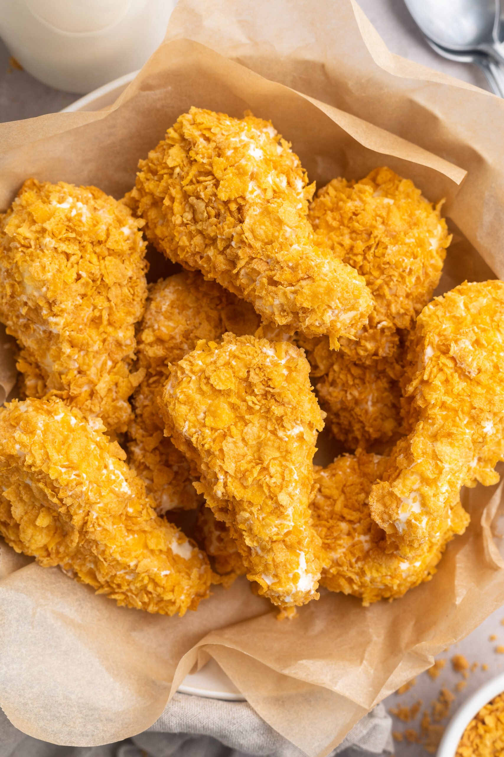 Overhead, top-down view of fried chicken ice cream drumsticks in a bowl lined with parchment paper.