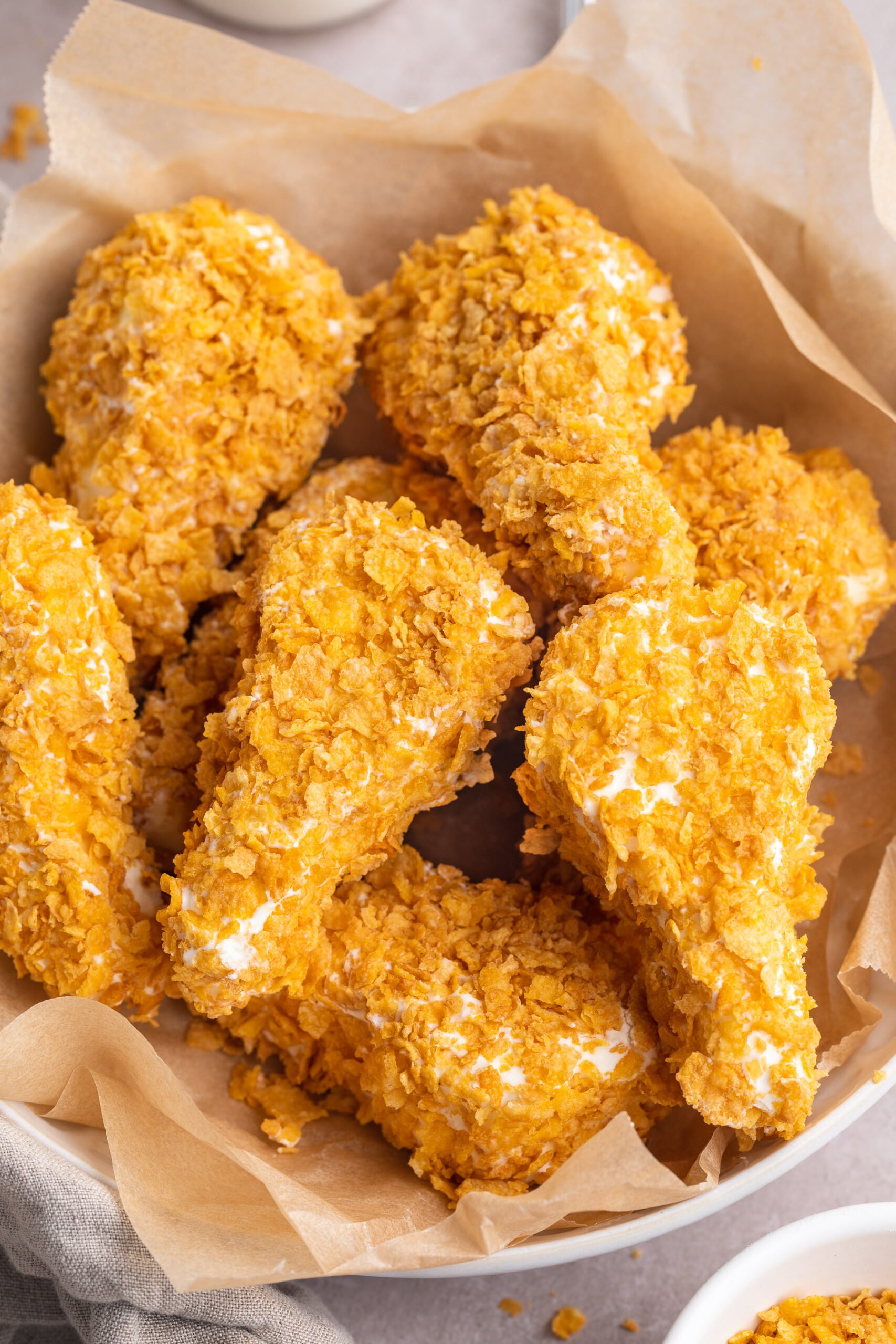 Overhead, top-down view of fried chicken ice cream drumsticks in a bowl lined with parchment paper.