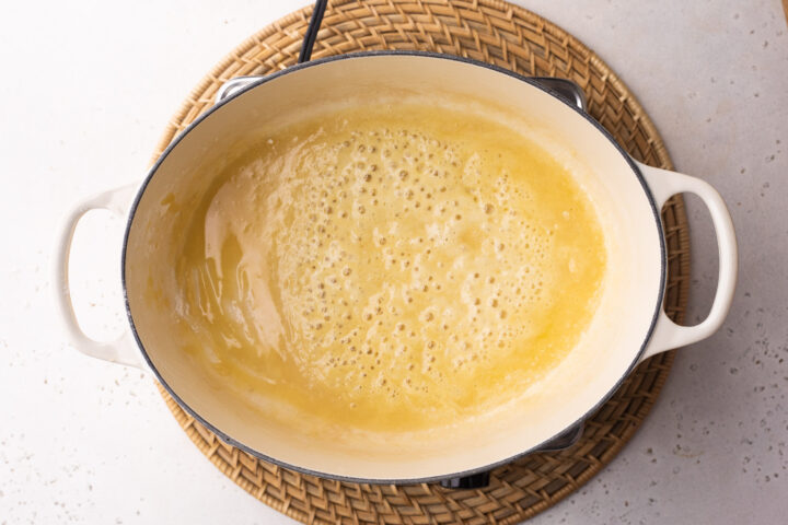 Overhead view of melted butter in a large oval baking dish with two handles.