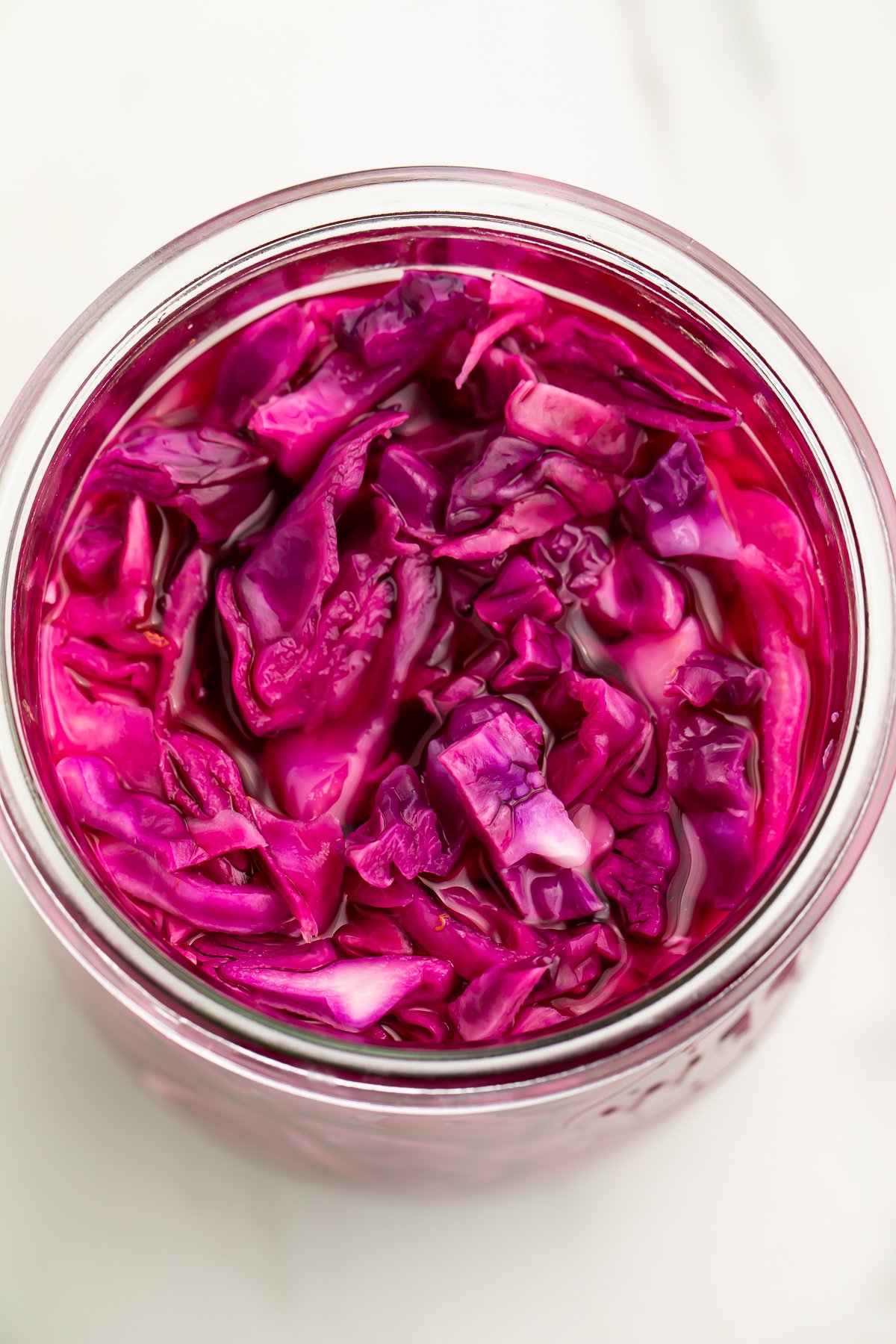 Top down view of pickled red cabbage in a large glass jar.