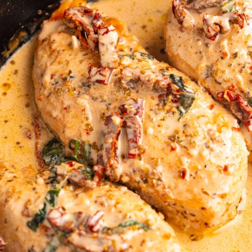 Marry Me Chicken breasts in a cast-iron skillet with basil and sun-dried tomatoes.