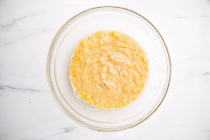 3 mashed bananas in a large glass mixing bowl.