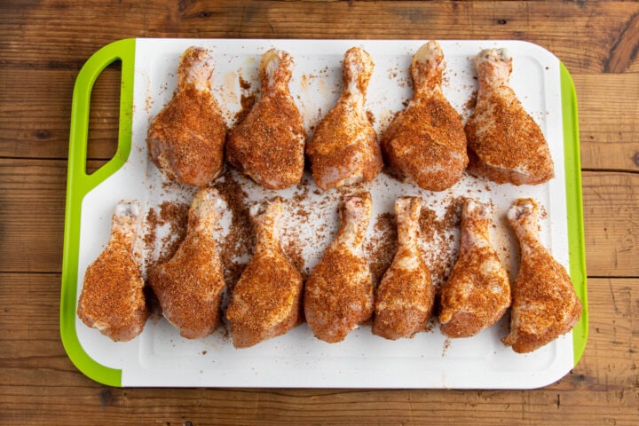 Dry rubbed chicken legs on a cutting board.