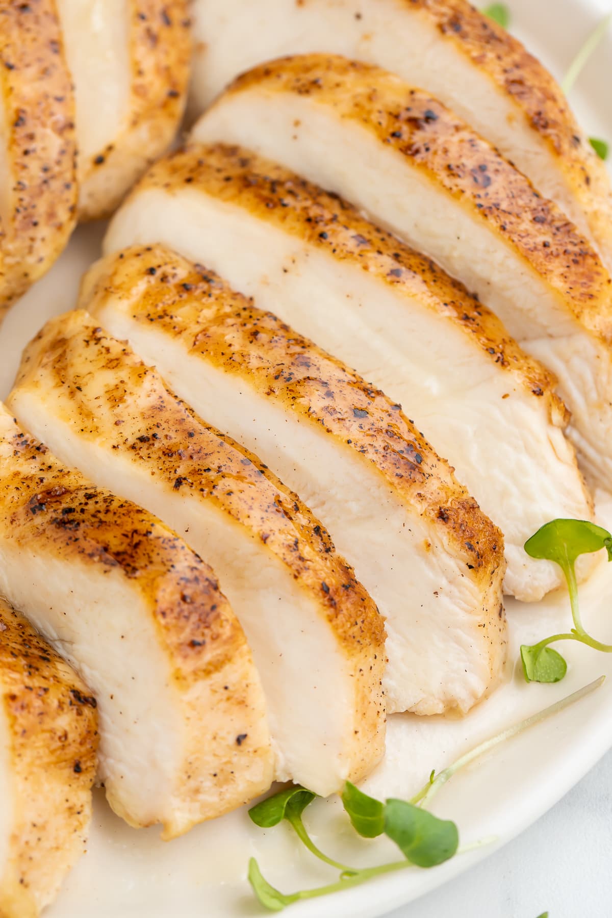 Sliced sous vide chicken breast arranged on a platter to show the juicy white meat and the seasoned skin at the same time.