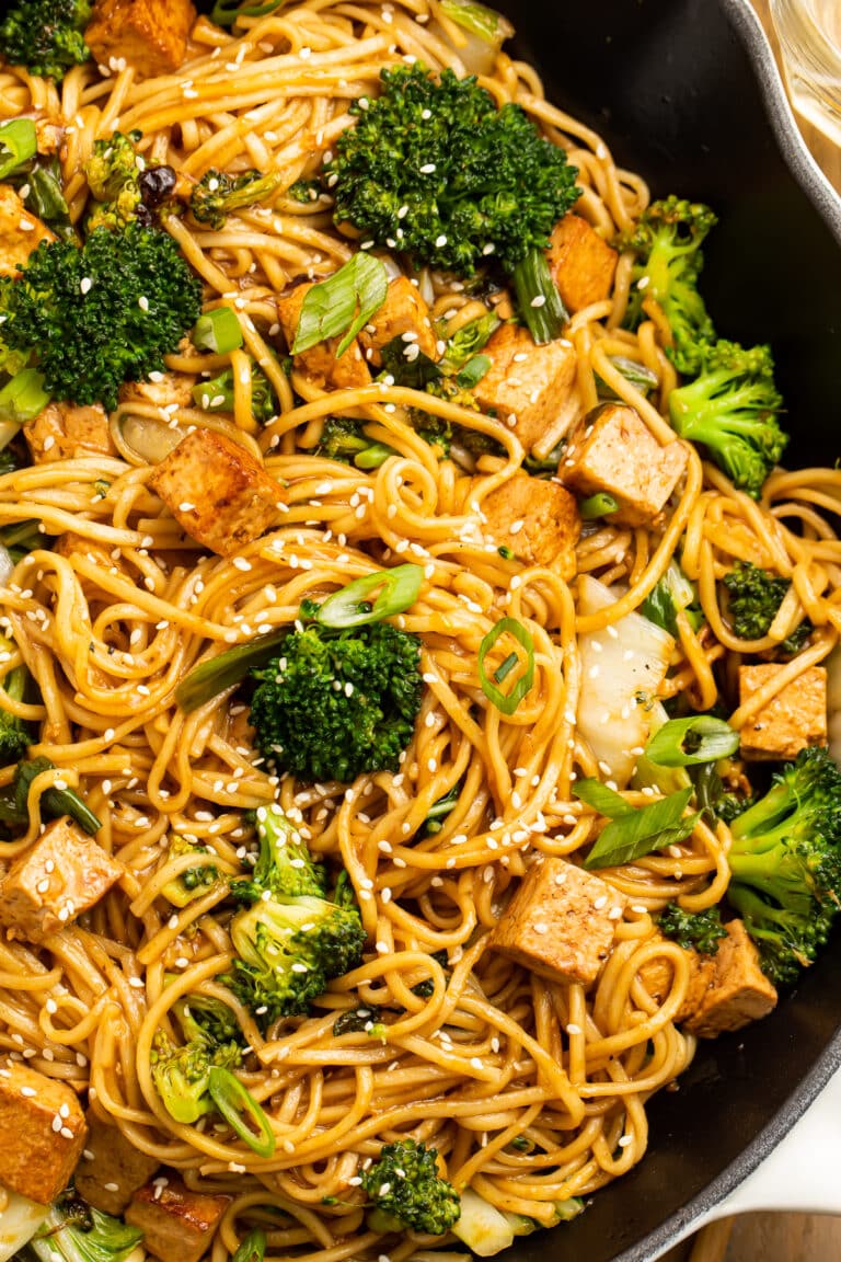 Close-up view of stir fry noodles with tofu and veggies in a cast iron skillet.