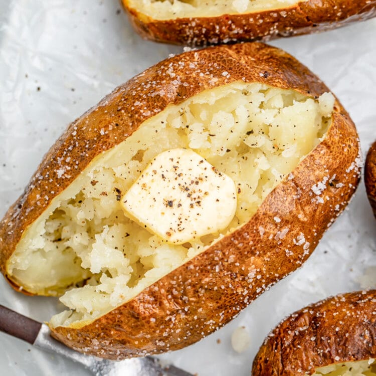 Air fryer baked potato crusted in salt, split in the middle and fluffed, then topped with butter and pepper.